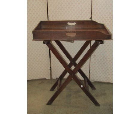 A 19th century oak butlers tray of rectangular form with pierced handles and raised on a simple folding stand, the tray 71 cm