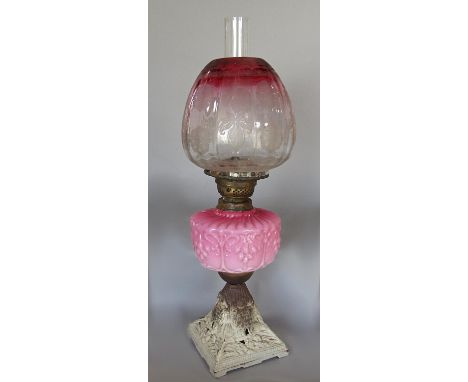 A Victorian oil lamp with pink font and rose tinted shade 