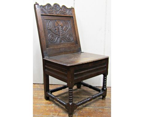 An 18th century oak side chair, the back with carved and decorated finish beneath a shaped cresting rail, raised on bobbin mo