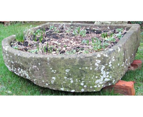 A large weathered shallow D shaped natural stone trough, 118cm wide x 108cm deep x 25cm high (af) (old crack/repair) 