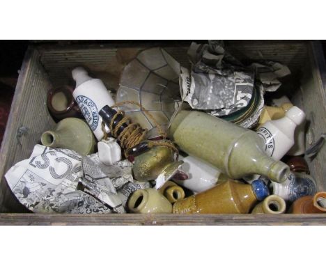 A distressed canvas covered wooden trunk containing an assorted collection of earthenware bottles 