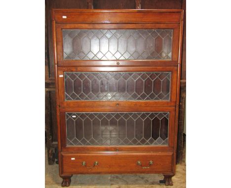 A Globe Wernicke style four sectional floorstanding library bookcase enclosed by up and over leaded light glazed rectangular 