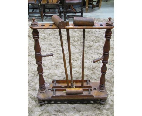 A Victorian croquet stand in pine with ring turned and tapered columns, pierced circular mallet receptacles on a platform bas
