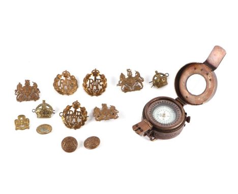 A WWII style military field compass; together with assorted military cap badges.