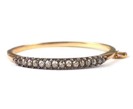 A 19th century yellow metal diamond set hinged bangle set with sixteen graduated diamonds, the largest diamond approx 5 by 4m