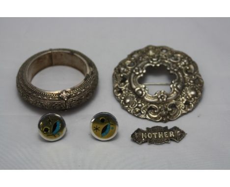 A MIDDLE EASTERN WHITE METAL BANGLE, a brooch, a silver Mother brooch and a pair of silver earrings (4)