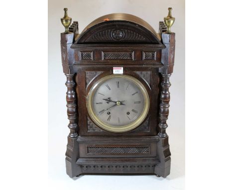 A circa 1900 continental oak cased mantel clock, having eight-day movement, the silvered dial showing Roman numerals, the cas