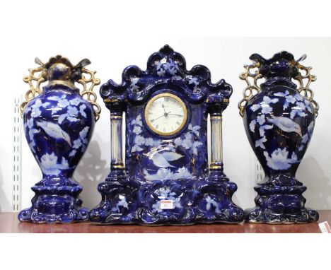 A 20th century blue and gilt decorated pottery clock garniture, of architectural form, having quartz movement, h.47cm