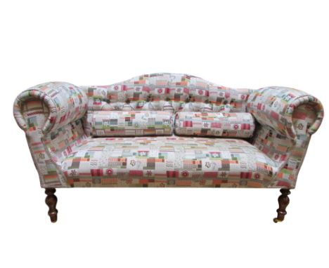 A small contemporary sofa with arched back and scrolled arms on turned supports, with bright patterned fabric upholstery