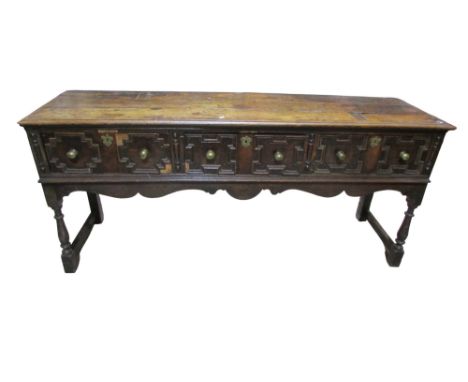 An 18th century oak dresser enclosed by three drawers with geometric block work detail with shaped frieze and turned supports
