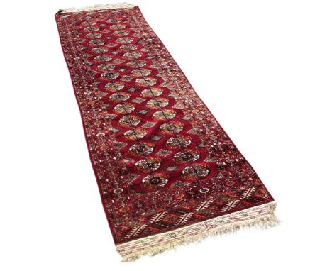An Afghan runner with two rows of small guls on a red ground, 265cm x 80cm approximately