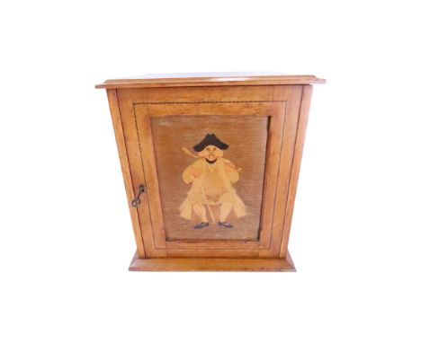 A 19th century oak smoker’s cabinet with an inlaid pipe smoker to the door opening to a fitted interior with two drawers and 
