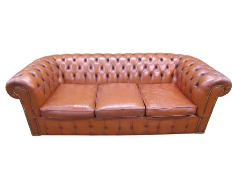 A vintage Chesterfield sofa, upholstered in a pale red leather, with buttoned finish