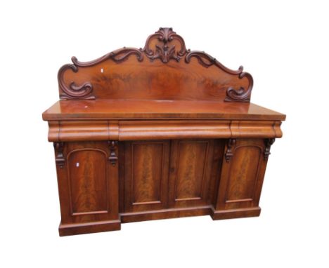 A small Victorian mahogany inverted breakfront sideboard enclosed by four doors and three drawers with raised and shaped back