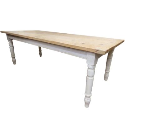 A traditional farmhouse kitchen table, the plank top with cleated ends and waxed finish raised on a painted frame with frieze
