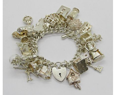 Heavy 1970s silver charm bracelet with heart padlock clasp, hung with numerous good novelty charms to include a corkscrew, we