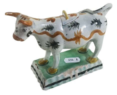 An 18th century Staffordshire 'Prattware' ceramic cow creamer and lid, with hand painted detail