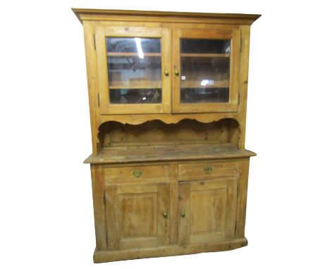 An antique continental stripped pine kitchen dresser in two sections enclosed by an arrangement of cupboards and drawers, 213