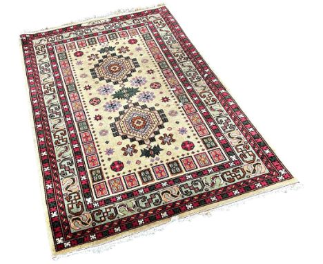 A small Persian style rug with two geometric medallions on a khaki ground with a signature, 170cm x 107cm approximately