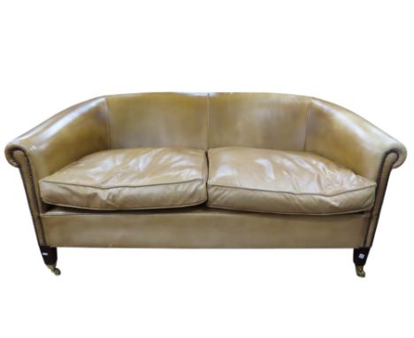 A good quality two seat sofa in pale tan leather raised on square tapered legs, with brass cup castors, 160cm long