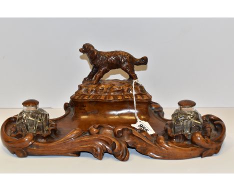 A WALNUT DESK STANDISH, having covered stamp/stationery compartment, cover with a spaniel finial, twin glass inkwells with wa