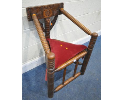 AN EARLY 20TH CENTURY OAK TURNERS CHAIR, with carved geometric designs, turned sloped armrests, dished triangular seat, raise