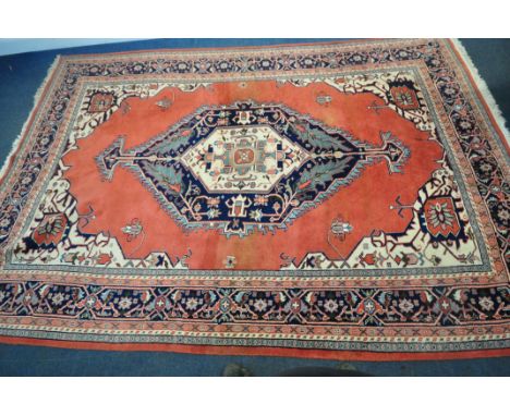 A LARGE RECTANGULAR RED GROUND WOOLLEN RUG, with a central medallion, repeating geometric patterns, surrounded by a multi-str