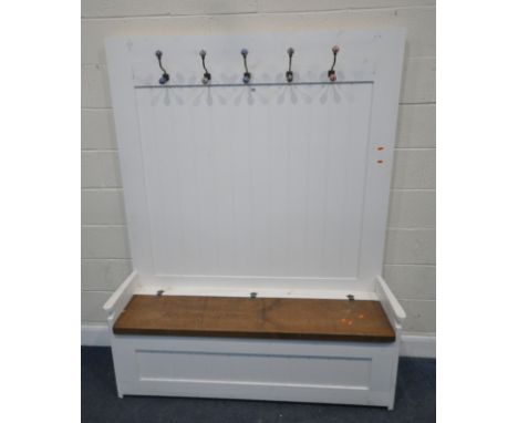 A PARTIALLY WHITE PAINTED SETTLE, with five coat hooks, a shelf, and a hinged seat, width 151cm x depth 44cm x height 188cm, 