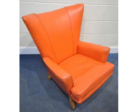 POSSIBLY G PLAN, A MID-CENTURY CORAL ORANGE LEATHERETTE WING BACK ARMCHAIR, raised on square tapered legs, width 78cm x depth
