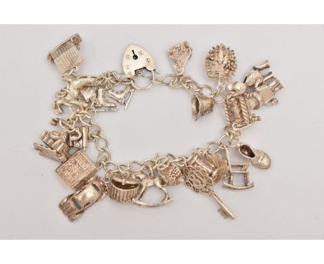 A SILVER CHARM BRACELET, a silver curb link bracelet fitted with a heart padlock clasp, hallmarked London, fitted with twenty