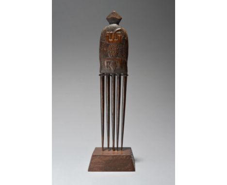 An Ashanti comb Ghana with five prongs and a carved handle with a raised lizard, 23cm long, on a stand. (2)