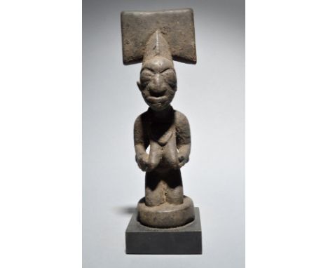 A Yoruba Shango staff finial Nigeria with a kneeling female figure and a thunder axe crest, with an encrusted patina, 25.5cm 