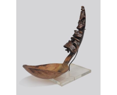 A Northwest Coast ladle goat horn with carved totemic heads to the handle, with inlaid shell eyes, with a copper repair to th