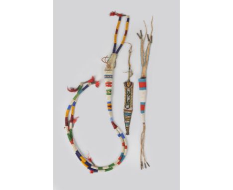 A Plains awl case buckskin and coloured glass beads, with feathered tin cones, 100cm long, a Comanche awl case, leather, bead