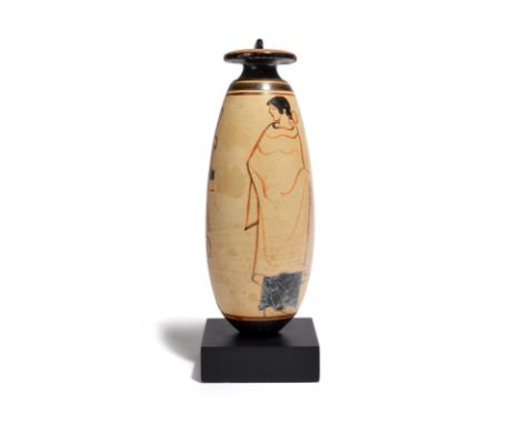 An Attic black-figure white ground alabastron circa 5th century BC decorated with a standing draped male figure, a palm tree,