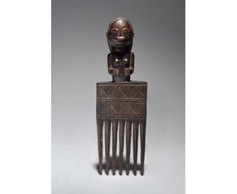 A Chokwe figural comb Angola the half female figure with a loop coiffure and with dimples to the face, 21cm high.