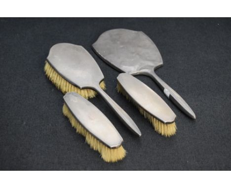 A George VI silver backed four piece brush set, comprising hand mirror, hair brush and two clothes brushes, each with engine-