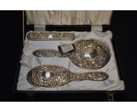 A Queen Elizabeth II silver mounted four-piece dressing table set, comprising hand mirror, hair brush, clothes brush and comb