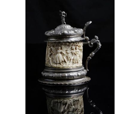 λ A late 19th century German silver mounted ivory historismus tankard, in 17th century style, the hinged lid with a putto fin