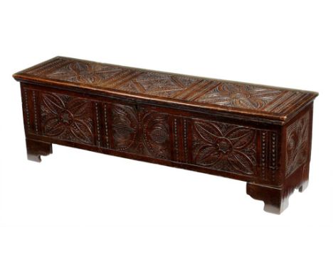 A 17th century boarded oak six plank chest, the hinged lid carved with panels of stylised flowers, the interior with a lidded
