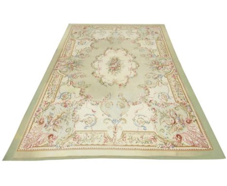 A large Aubusson style woven carpet, decorated with a central medallion of flowers, with foliate borders and corner trophies 