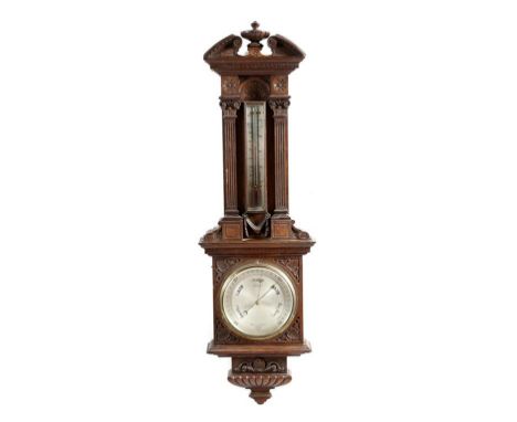 A late Victorian oak wall barometer by Negretti & Zambra, with a carved architectural case with a silvered thermometer above 