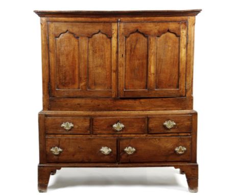 A George III Welsh oak press cupboard, with a pair of Gothic panelled doors enclosing a shelf, above three short and two long