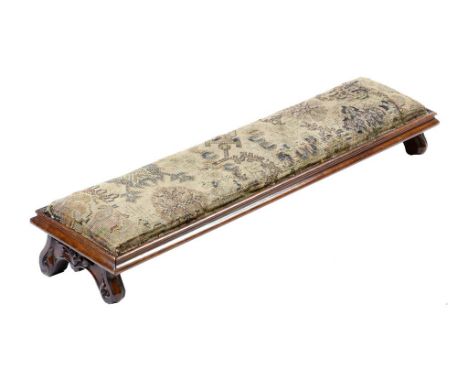 A Victorian walnut fender stool, with a needlework seat on carved feet, 17cm high, 109.6cm long, 26cm deep.