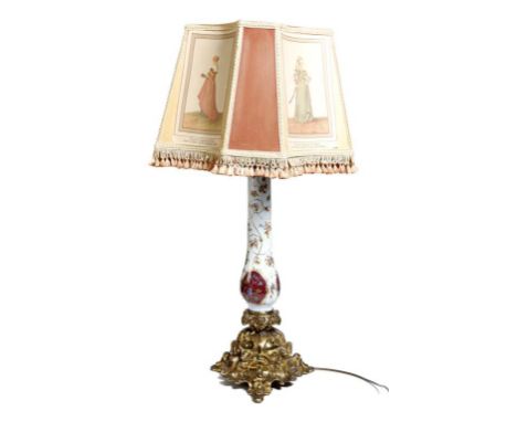 A mid 19th century opaline and gilt brass table lamp, painted with panels of flowers on a Rococo triform base, the shade with