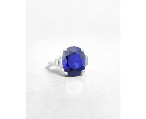 A SAPPHIRE AND DIAMOND RINGSet with a cushion-shaped sapphire, weighing 12.56 carats, between baguette-cut diamond shoulders,