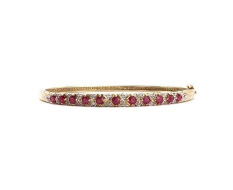 A 9ct gold ruby and diamond hinged bangle,a row of round mixed cut ruby claw set between pairs of eight cut diamonds, to scro