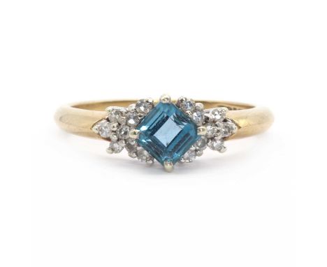 A 9ct gold topaz and diamond ring,a step cut blue topaz offset to a clawed collet, with a cluster of eight cut diamonds on ea