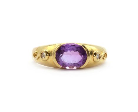 An 18ct gold amethyst and diamond three stone ring,with an oval mixed cut amethyst rub set to a semi bezel collet, with diamo