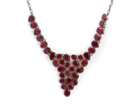 A silver and opaque ruby bib style necklace,with a series of oval and pear shape flat cut opaque rubies, all rub set in plain